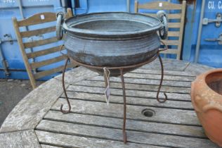 A copper vessel on wrought iron stand.