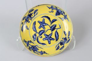 A CHINESE YELLOW GROUND CIRCULAR DISH with blue foliage. 9ins diameter.