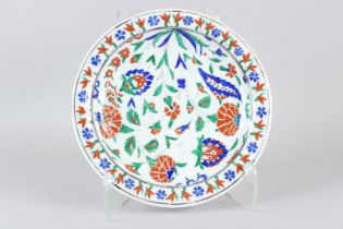 AN OTTOMAN TURKISH IZNIK CIRCULAR DISH, with stylised floral painted decoration. 31cms diameter.