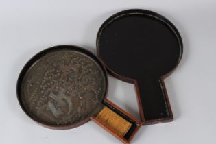 A JAPANESE BRONZE HAND MIRROR with wicker bound handle, the face with herons and foliage. 9ins