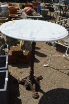 A circular marble table with cast iron base.