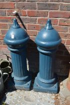 A pair of blue painted reconstituted stone bollards.