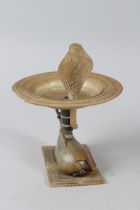 A VERY FINELY CARVED 19TH CENTURY INDIAN HORN FIGURE OF NANDI BULL carrying a lotus shaped dish,