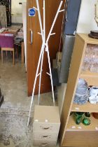 A white clothes rack and a small chest of three drawers.