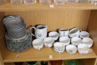 A shelf of French porcelain plates, tea cups, saucers and milk jug.