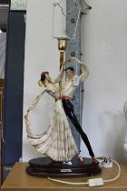 A pottery lamp with two figures dancing.