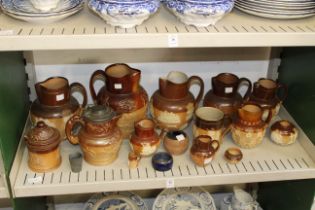 A shelf of good Royal Doulton jugs and other items.