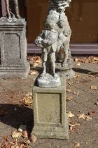 A garden statue of a boy on a plinth.