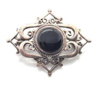 A silver and black onyx brooch.