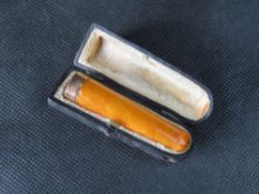 An amber cheroot holder having gold band (hallmark worn) in original fitted case.