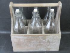 A contemporary bottle basket with six glass bottles.