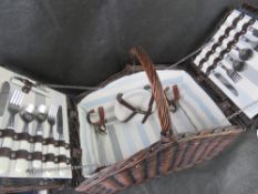 A wicker picnic basket with contents.