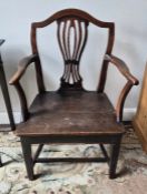 An antique Georgian oak carver chair having Hepplewhite influenced design with a central pierced