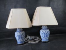 A pair of blue and white Chinese ginger jar style lamps with cream shades.