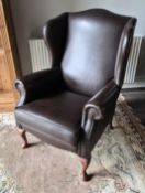 A contemporary faux leather wingback armchair.