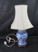 A blue and white Chinese ginger jar style lamp with cream shade.