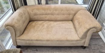 A small beige two seater Chesterfield stye settee.