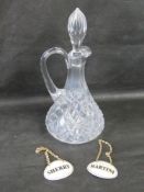 A cut glass jug with stopper and two drinks labels.