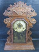 An American eight day mantle clock, having carved wooden case and gilded decoration to glass front.