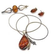A suite of Baltic amber and silver jewellery comprising pendant on chain, brooch and earrings.