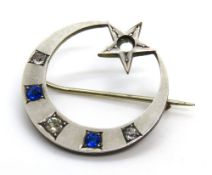 A crescent moon brooch set with blue and white paste stones.
