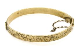 A 9ct gold metal core bangle, foliate engraving to front.