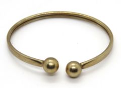 A 9ct gold bangle having ball terminals, hallmarked 375, 9.7g.