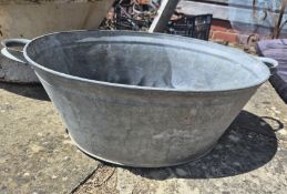 A galvanized metal basin with twin end handles.