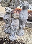 Two concrete garden figurines of meerkats plus one plastic similar.
