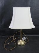A brass table lamp with cream shade.