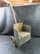 An antique green wooden doll buggy featuring long wooden pull handle with folding footrest