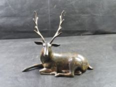 A 20th century rustic bronze-patina sculpture of a resting deer.