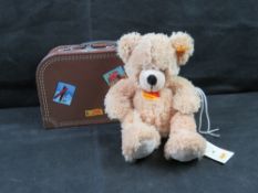 A Steiff 'Fynn' bear in cardboard-style brown travel suitcase box.