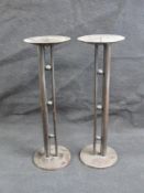 A pair of modernist style candle stands each standing 31cm high.