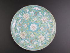 An Oriental blue ground dish having white floral decoration upon, 25cm diameter.