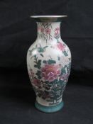 An Oriental vase with green and pink floral decoration on a cream background, standing 30cm high.
