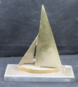A mid-century modern sailboat figurine crafted from solid brass and stood on marble base.