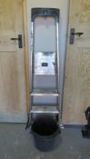 An aluminium step ladder and two black plastic buckets.