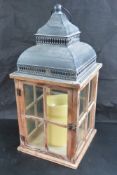 A single contemporary glazed wooden lantern containg battery powered candle standing 51cm high.