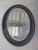 A large oval wall mirror in heavily carved wooden frame,