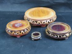 Four carved Oriental hardwood stands, largest 19cm diameter, smallest 4.