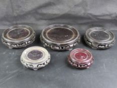 Five carved Oriental hardwood stands, largest 19cm diameter, smallest 9.5cm diameter.