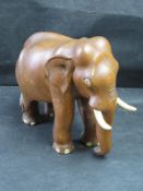 A carved wooden elephant having bone tusks, eyes and toes.