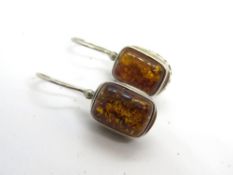 A pair of silver and amber earrings.