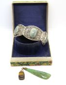 A Chinese white metal bangle together with a jade type pendant and a tigers eye pendant.