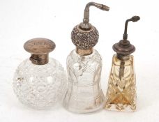 Two cut glass and sterling mounted atomisers together with a cut glass perfume bottle with a white