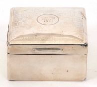 An Edwardian silver cigarette box of square form, the hinged slight domed lid chased and engraved