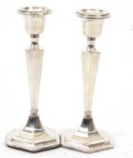 A pair of George V silver candlesticks of plain hexagonal form having tapering stems to a loaded