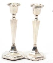 A pair of George V silver candlesticks of plain hexagonal form having tapering stems to a loaded