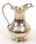 A Victorian silver jug of plain baluster form engraved with initials, having reeded rims and